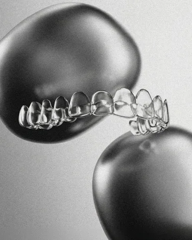 Gouttière transparente posée entre deux formes chromées : évocation des aligneurs transparents